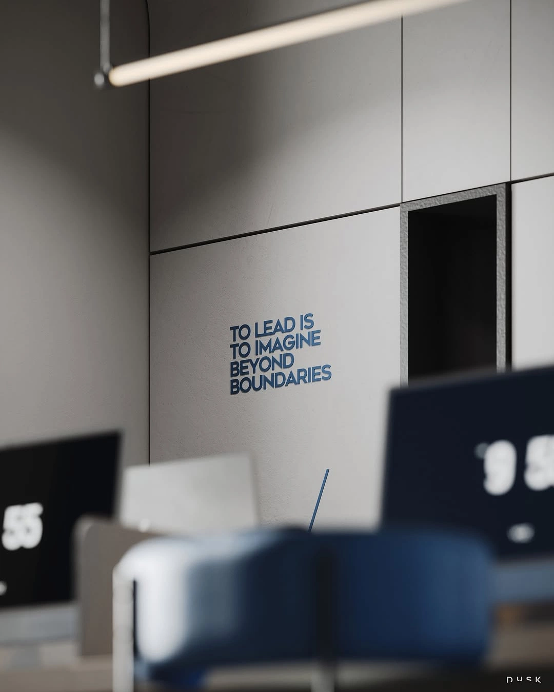 A grey studio wall lettered “To lead is to imagine beyond boundaries”, above blurred desks and monitors